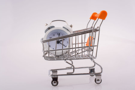 Alarm clock in a shopping trolley on white backgroundの写真素材