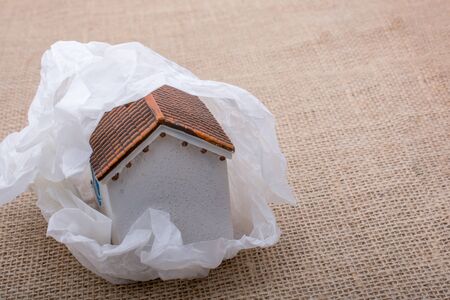 Little model house wrapped in paper on a brown backgroundの写真素材