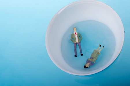 Little model globe with  figurines  floating in blue waterの写真素材