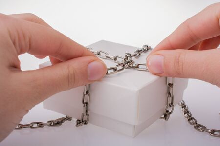 Hand holding a gift box with a chain aroundの写真素材