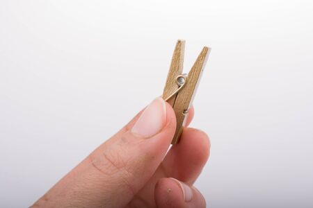 Hand holding a small wooden clothespin in handの写真素材