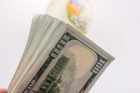 American dollar banknotes by the side of a model globe on white background