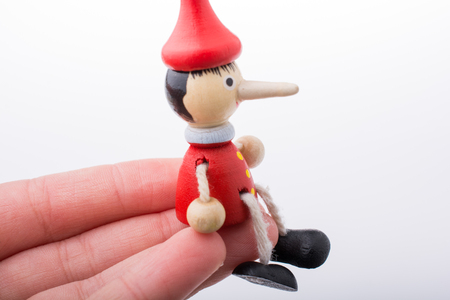Wooden pinocchio doll in hand on a white backgroundの写真素材