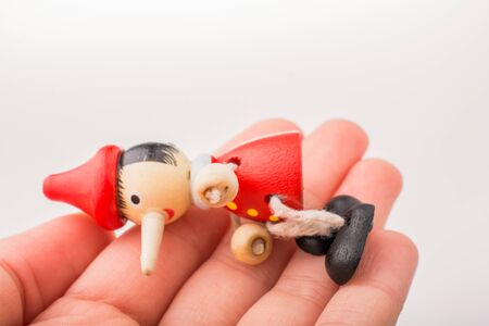 Wooden pinocchio doll in hand on a white backgroundの写真素材