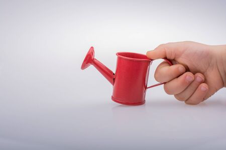 Hand holding a watering can on a white backgroundの写真素材
