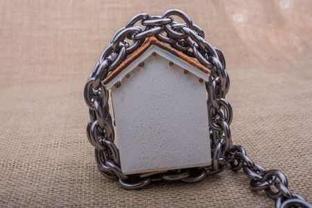 Chain wrapped around  a model house  on a brown backgroundの写真素材