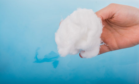 Hand holding some cotton in hand over blue water