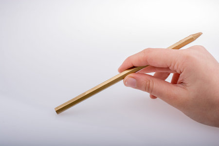 Hand holding a gold color pencil on a white backgroundの写真素材