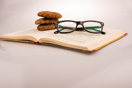 Chocolate chip cookies and glasses placed on a book