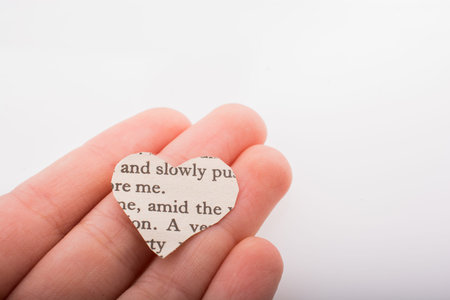 Hand holding a heart shaped burnt out of a texted paper