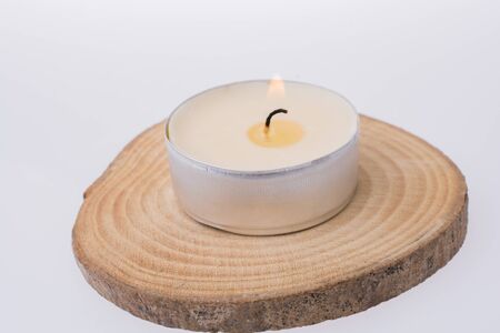 Candle placed  on a piece of wood on a white backgroundの写真素材
