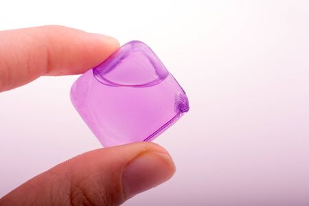 Hand holding fake colorful ice cube on a white backgroundの写真素材