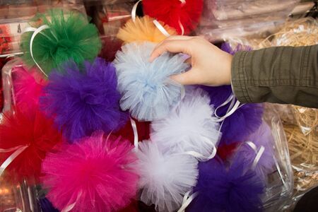 Hand holding a pompom among set of different colours a pompomsの写真素材