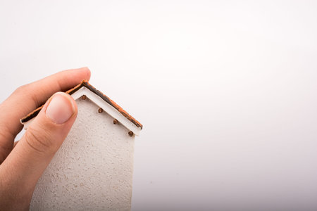 Little model house and  a hand  on a light  brown color background