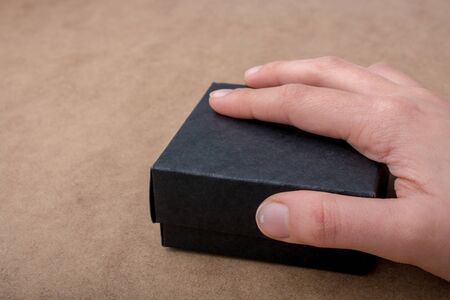 Hand holding a gift box of black color in handの写真素材