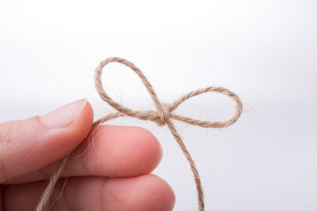 Thread knot in hand on a light color backgroundの写真素材