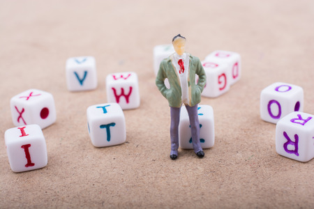 Figurine standing in front of the colorful alphabet letter cubesの写真素材