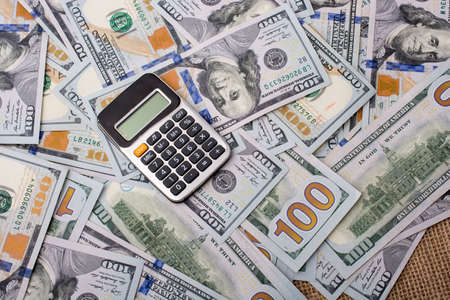 Calculator is placed on  the banknote of US dollars spread aroundの写真素材