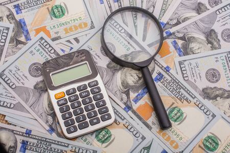 Magnifying glass is held over the banknote bundle of US dollarの写真素材