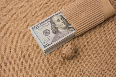 Spool of linen spool is placed on bundle of US dollar banknotes