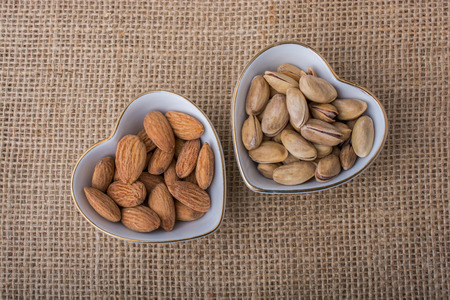 Peanuts, almonds, pistachio  in heart shaped plates on canvasの写真素材