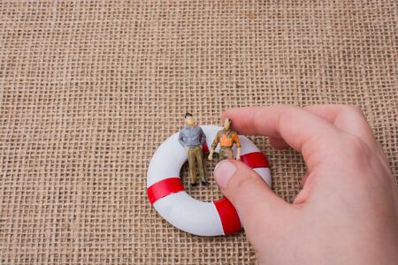 Hand  holding a figurine man in a life preserver on life on canvasの写真素材