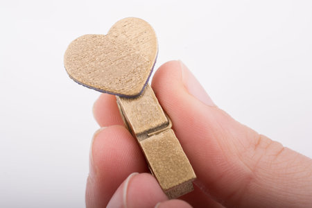 Heart shape icon  attached to a clothespin in hand