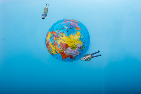 Little globe with    floating figurines around in waterの写真素材