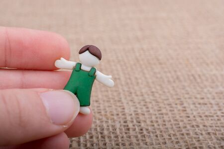 Little child figurine in hand on a brown backgorundの写真素材