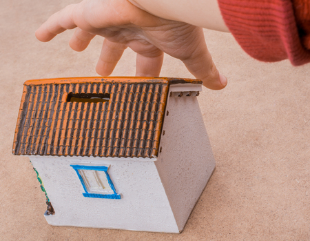 Little model house and  a hand  on a light  brown color backgroundの写真素材
