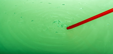 Watercolor paint dissolving in water as painting brush touches water