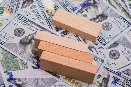 Wooden building blocks placed on spread US dollar Banknotesの写真素材