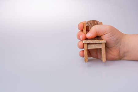 Child holding a brown color wooden  toy chair on white backgroundの写真素材