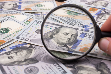 Magnifying glass is held over the banknote bundle of US dollarの写真素材
