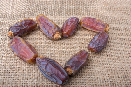 Date fruit form a heart shape on canvas background