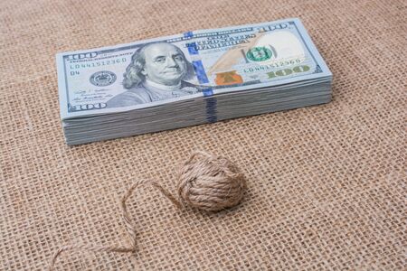 Spool of linen spool is placed on bundle of US dollar banknotesの写真素材