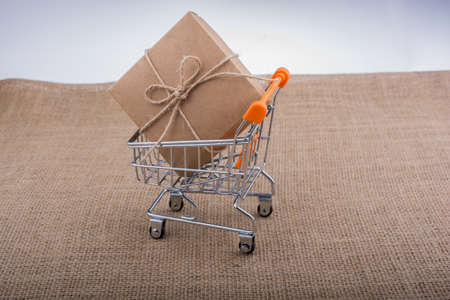 Gift box in shopping cart on a canvas backgroundの写真素材