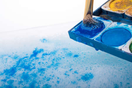 Watercolor paint dissolving in water covered with foamの写真素材