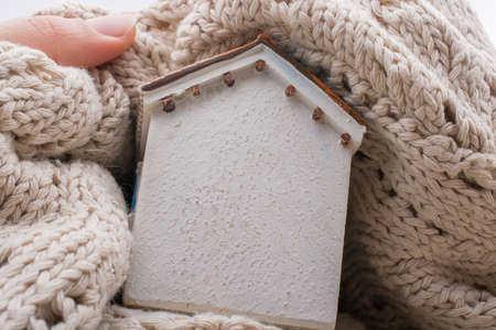 Little model house wrapped in cloth on a brown backgroundの写真素材