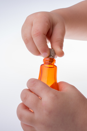 Child holding a little colorful empty glass bottle on a white backgroundの写真素材