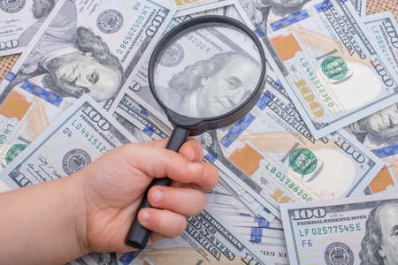 Magnifying glass is held over the banknote bundle of US dollarの写真素材