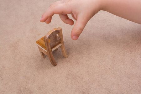 Child holding a  wooden  toy chair on brown backgroundの写真素材