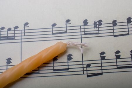 Candle placed on a paper with musical notesの写真素材