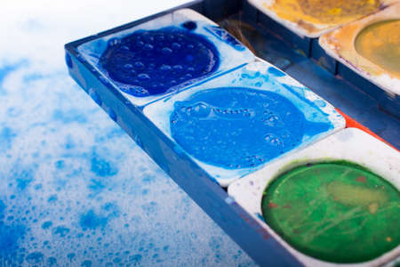 Watercolor paint dissolving in water covered with foamの写真素材