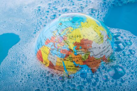 Paint brush placed on the top of globe in a water covered with foamの写真素材