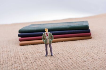 Man figurine standing beside little books on canvasの写真素材