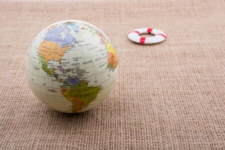 Life preserver beside a globe placed on canvas backgroundの写真素材
