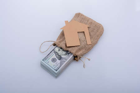 Paper house placed beside a bundle of US dollar banknoteの写真素材