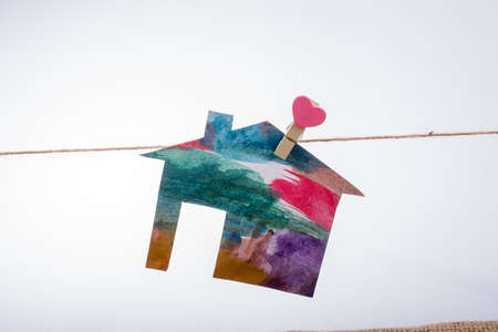 Little paper house attached to a string with a heart clipの写真素材