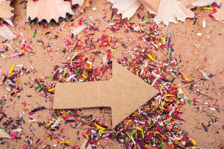 Arrow cut out of paper amid pencil shavings on canvasの写真素材
